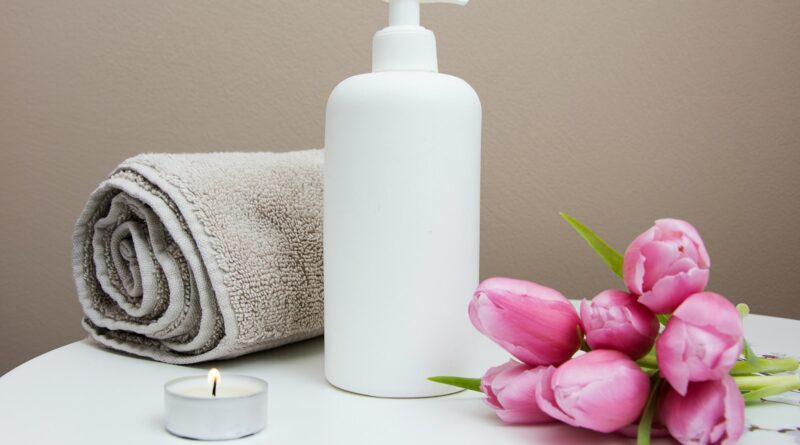 white plastic pump bottle beside pink tulips and gray towel